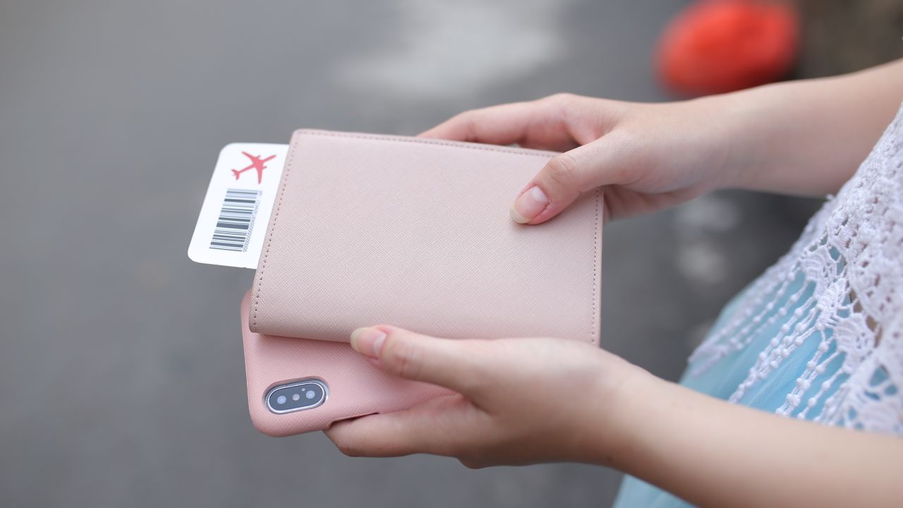 Traveller holding a passport wallet with a boarding pass and a smartphone before an international flight