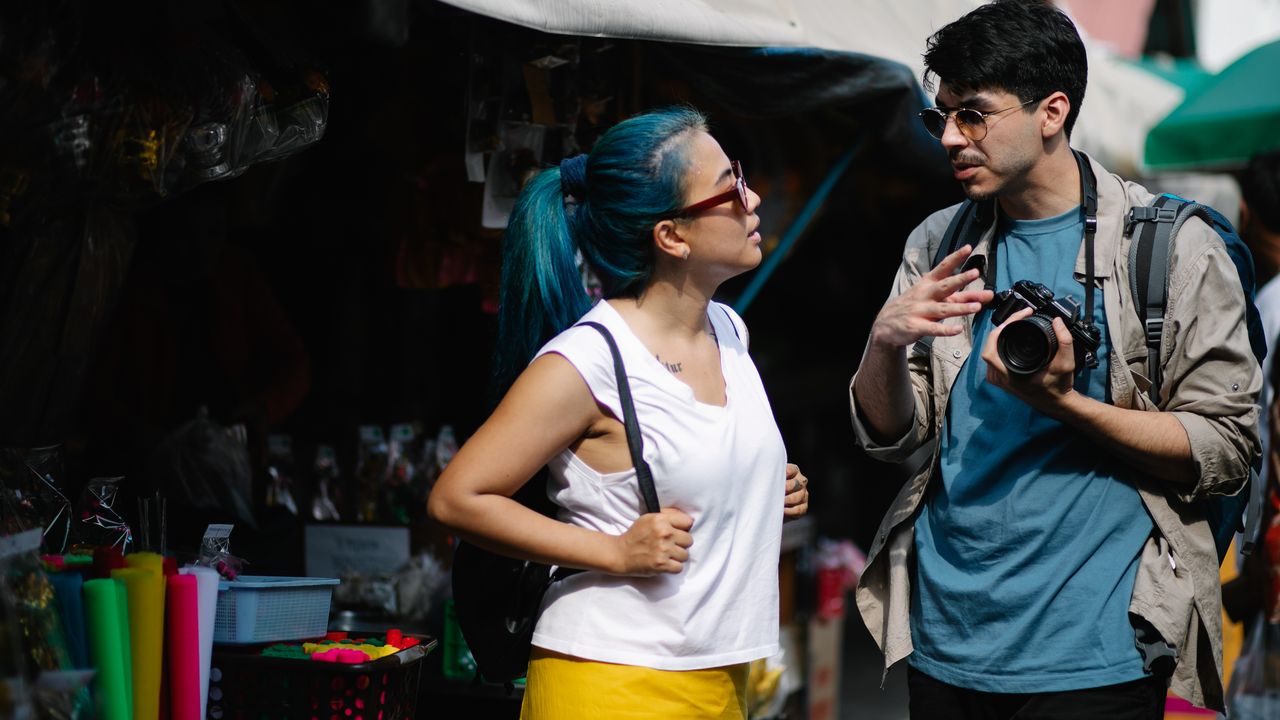 Travellers talking with each other in a busy street market, where Google Translate conversation mode needs data on most phones
