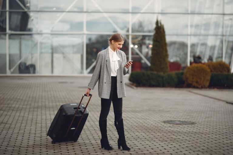 Traveler checking phone outside airport with suitcase — eSIM lets you set up data before you land