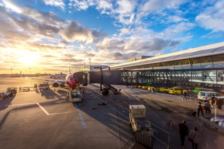 Traveler with luggage at airport arrivals trying to book Uber ride abroad — ride-sharing apps need mobile data