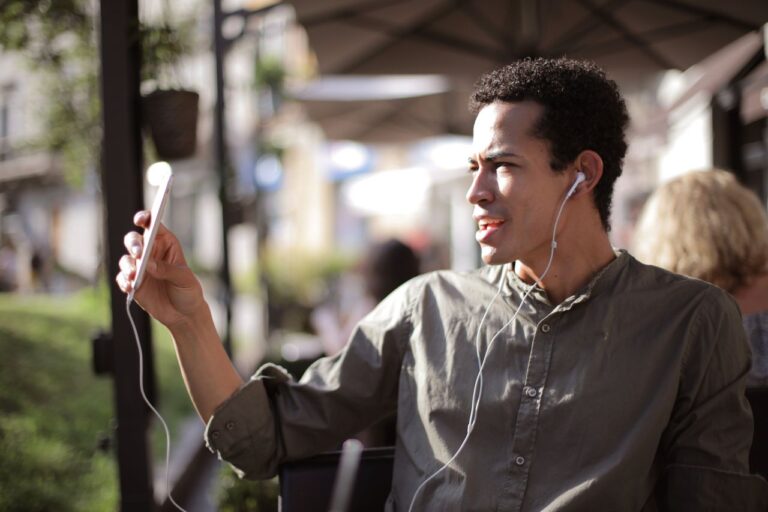 Man on outdoor terrace using smartphone for video call while traveling abroad — mobile data needed for WhatsApp and FaceTime